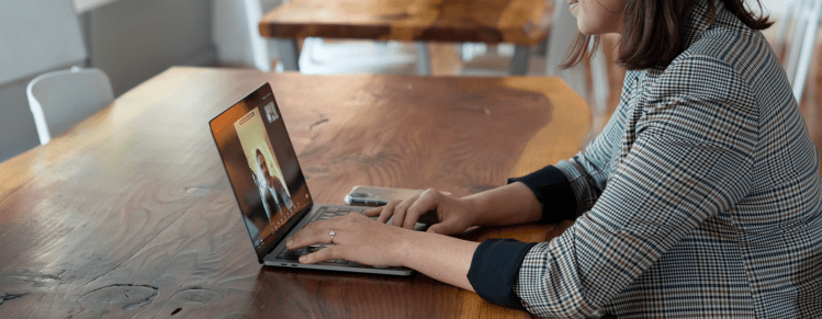 Woman at table with laptop, Virtual meeting in progress.